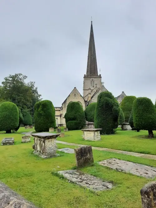 The church of St Mary's in Painswick, with its tall spire, lined yew trees and intriguing tombstones
