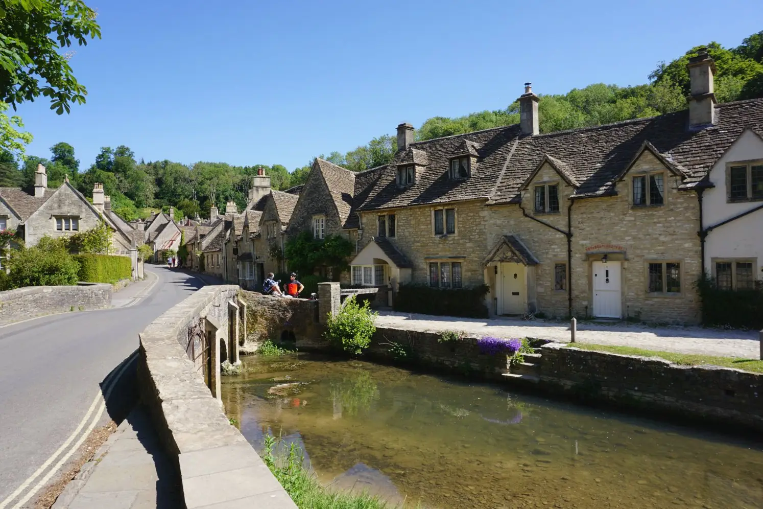 Picturesque Cotswold cottages and charming stream along the main road in Castle Combe
