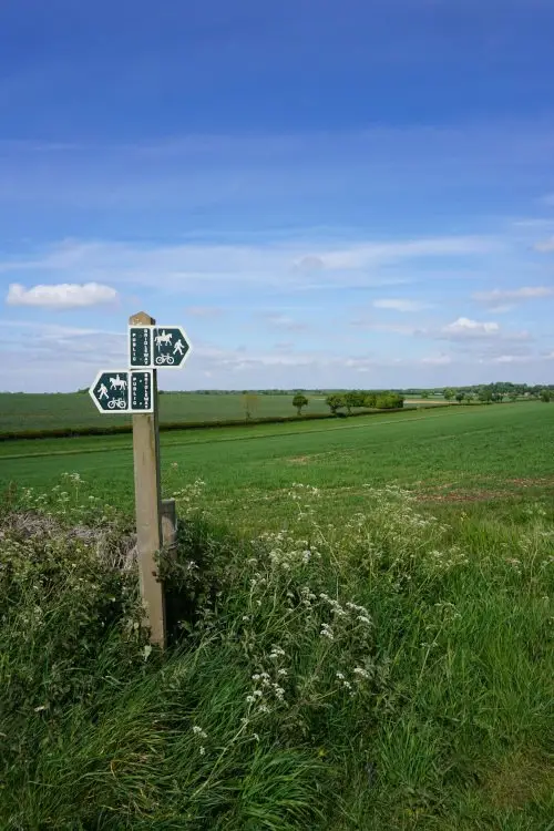 Rolling Cotswold countryside with a footpath signpost