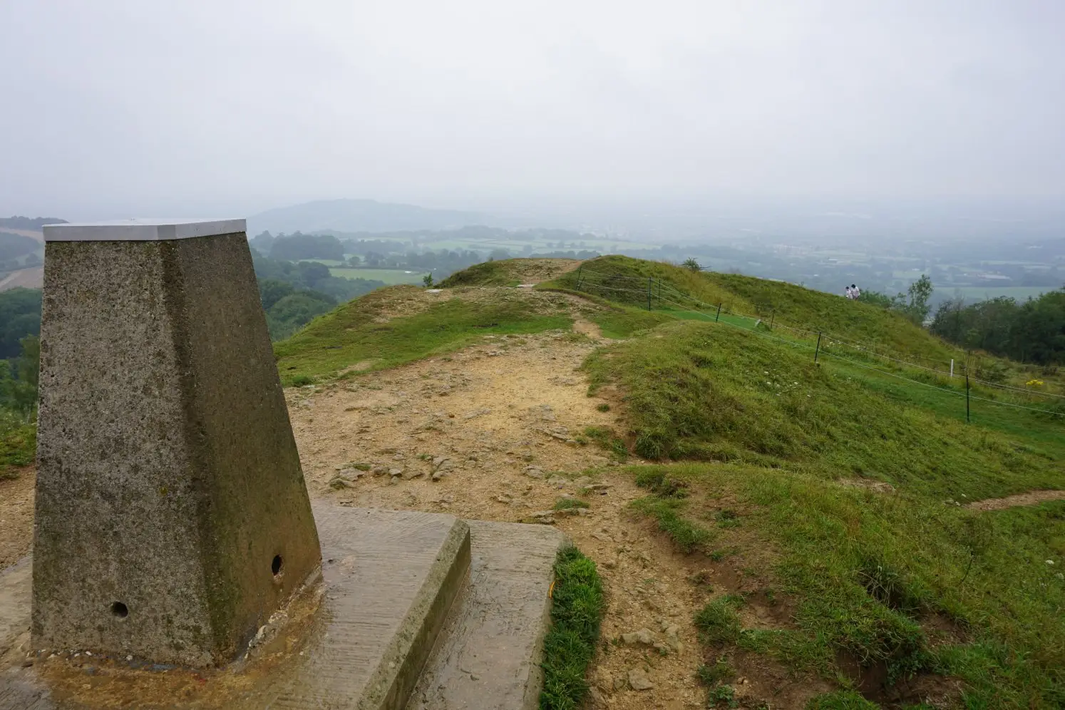 The trig point at Painswick Beacon and its hazy views on the Painswick Beacon & Painswick Valley walk