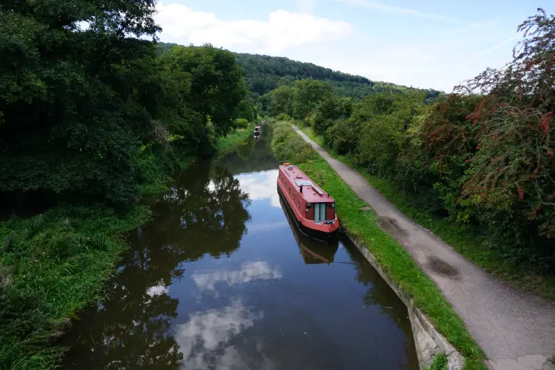 Canal boats moored to the banks and cruising on the waters on the Bath to Bradford-on-Avon canal walk