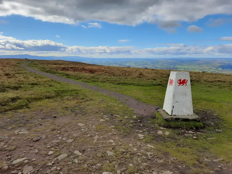 The trig point of Rhos Dirion in the Brecon Beacons emblazoned with the Welsh dragon