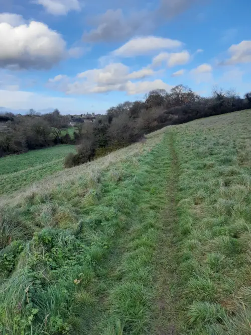 Walking through fields with views of Cotswold village ofSherston